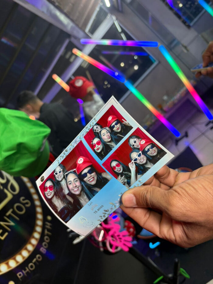 Convidados exibindo fotos impressas com bastões de LED ao fundo